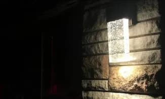 Modern outdoor LED wall sconce installed on stone exterior by Castle Electric serving Greater Boston MA