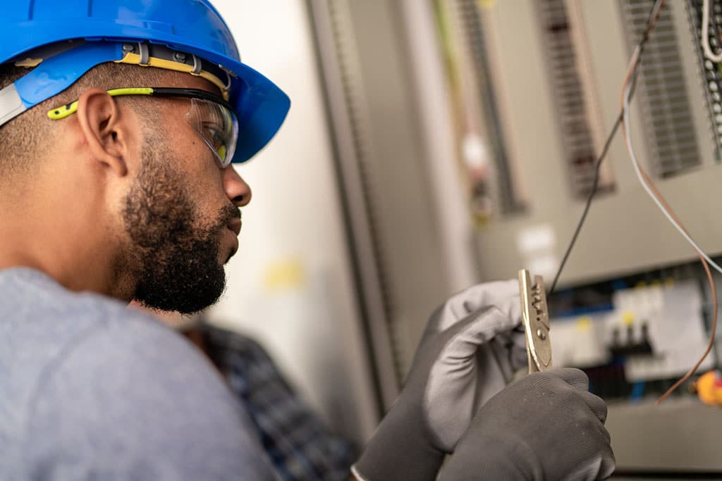 Electrician cutting wire with cutter as part of electrical safety inspection