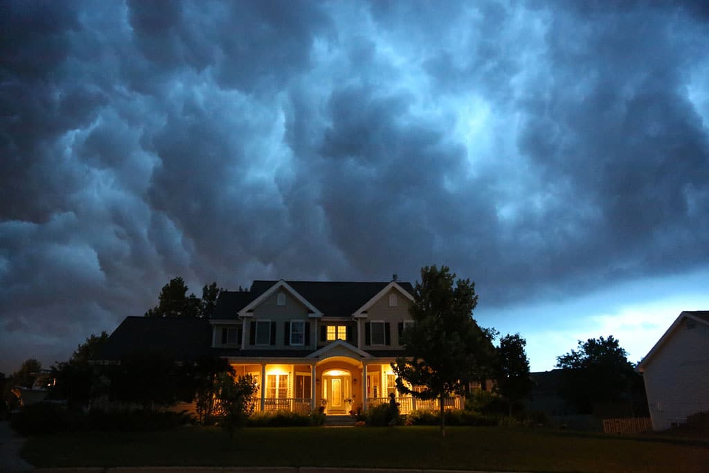 house lit up while a storm rolls in