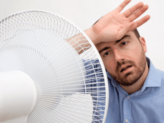 man in front of fan because he's too hot at home